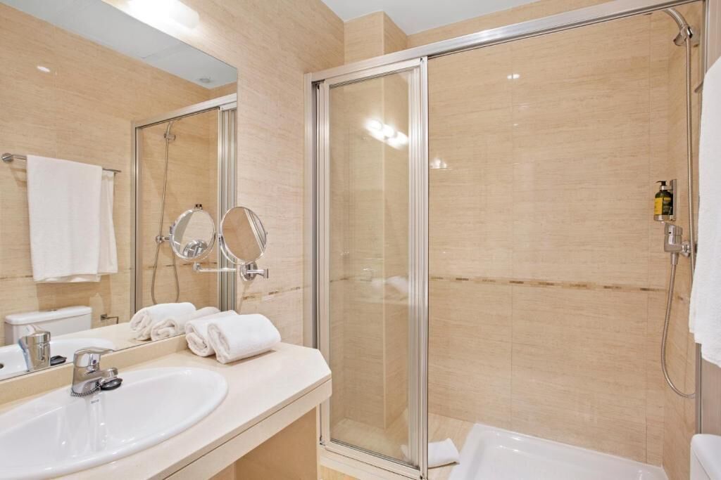 A modern bathroom with a glass shower enclosure, a sink with a mirror, and a toilet.