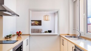 Una cocina moderna con horno integrado, un lavamanos y una ventana con vistas a una sala de estar.