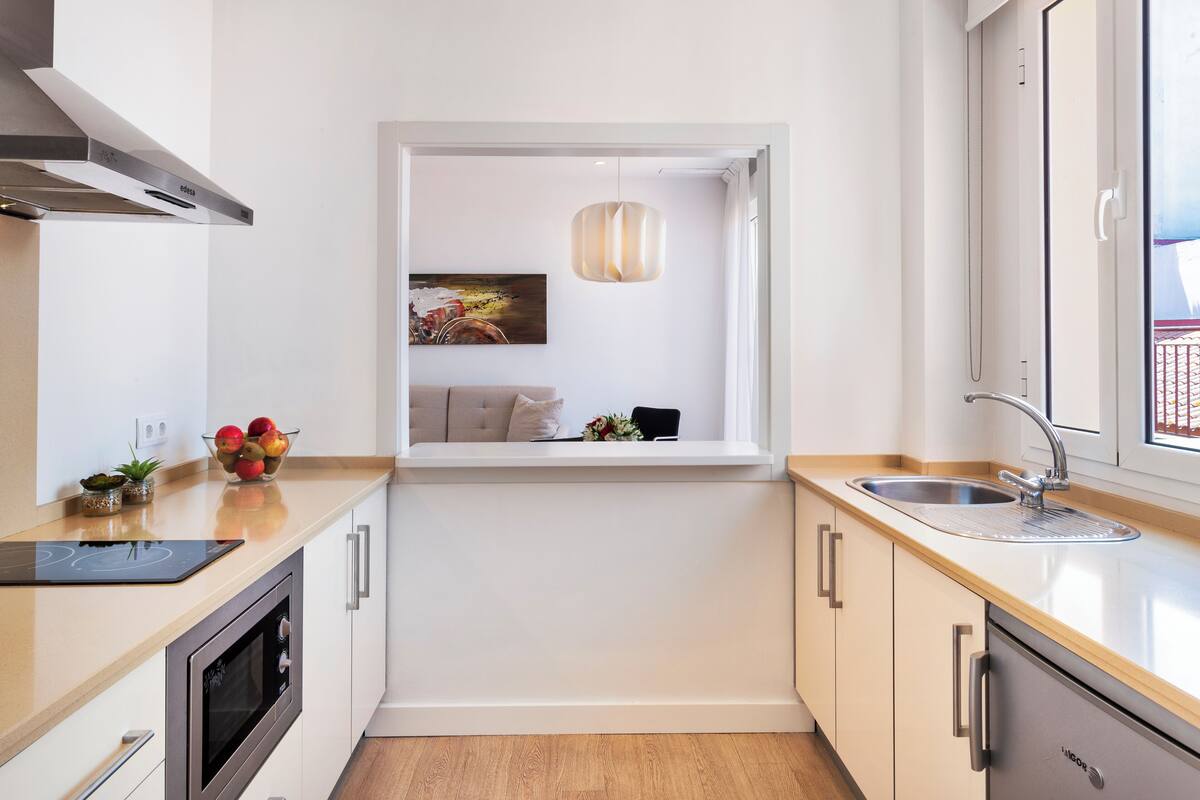 Una cocina moderna con horno empotrado, ventana con vistas y fregadero.