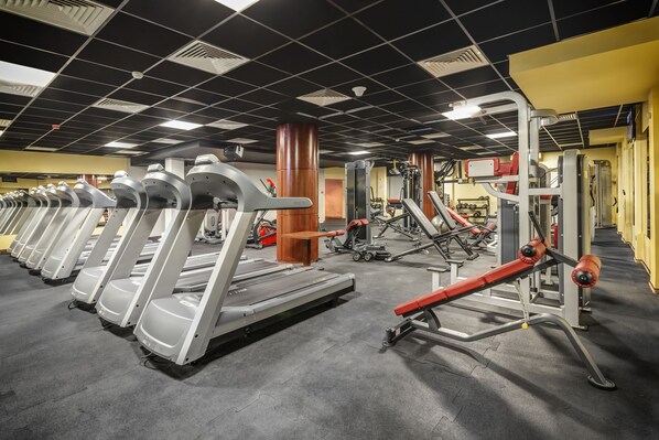 A gym with treadmills, weight machines, and a mirrored wall.