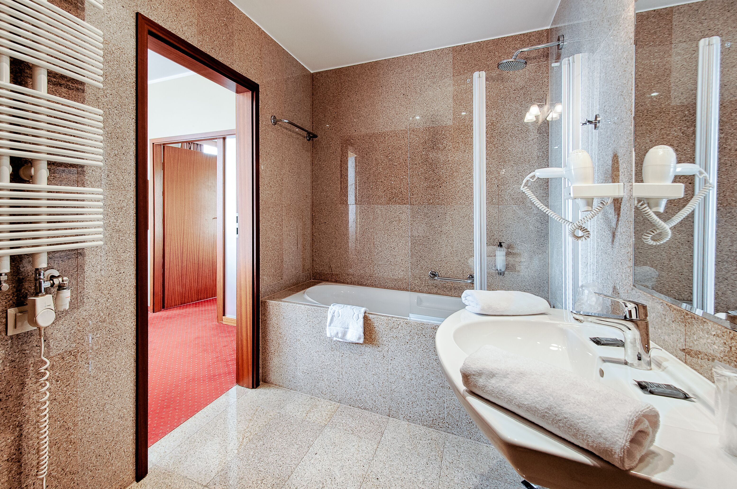 Ein modernes Badezimmer mit einer Badewanne, einem großen Spiegel und einem Waschtisch.