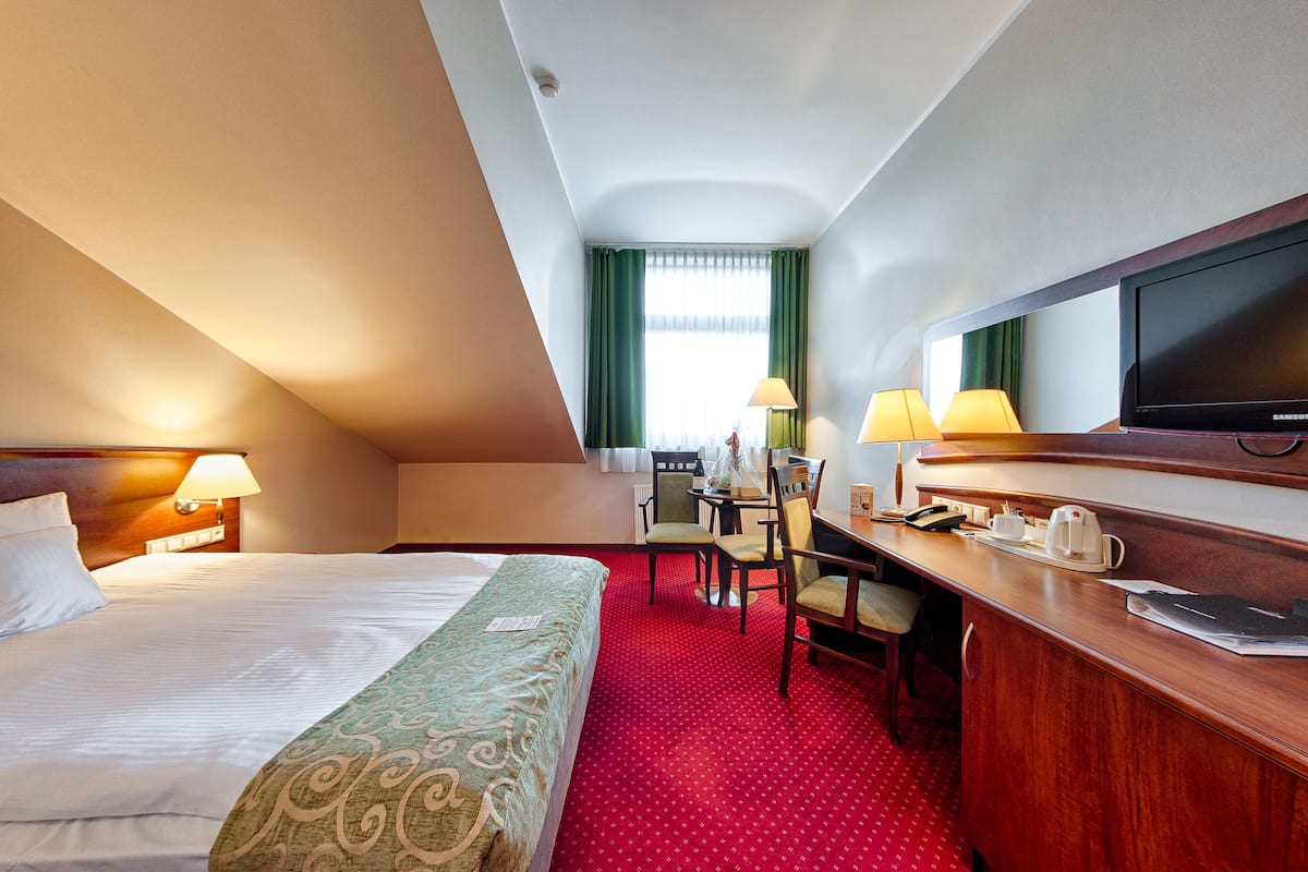 A hotel room with a bed, desk, chair, and television.