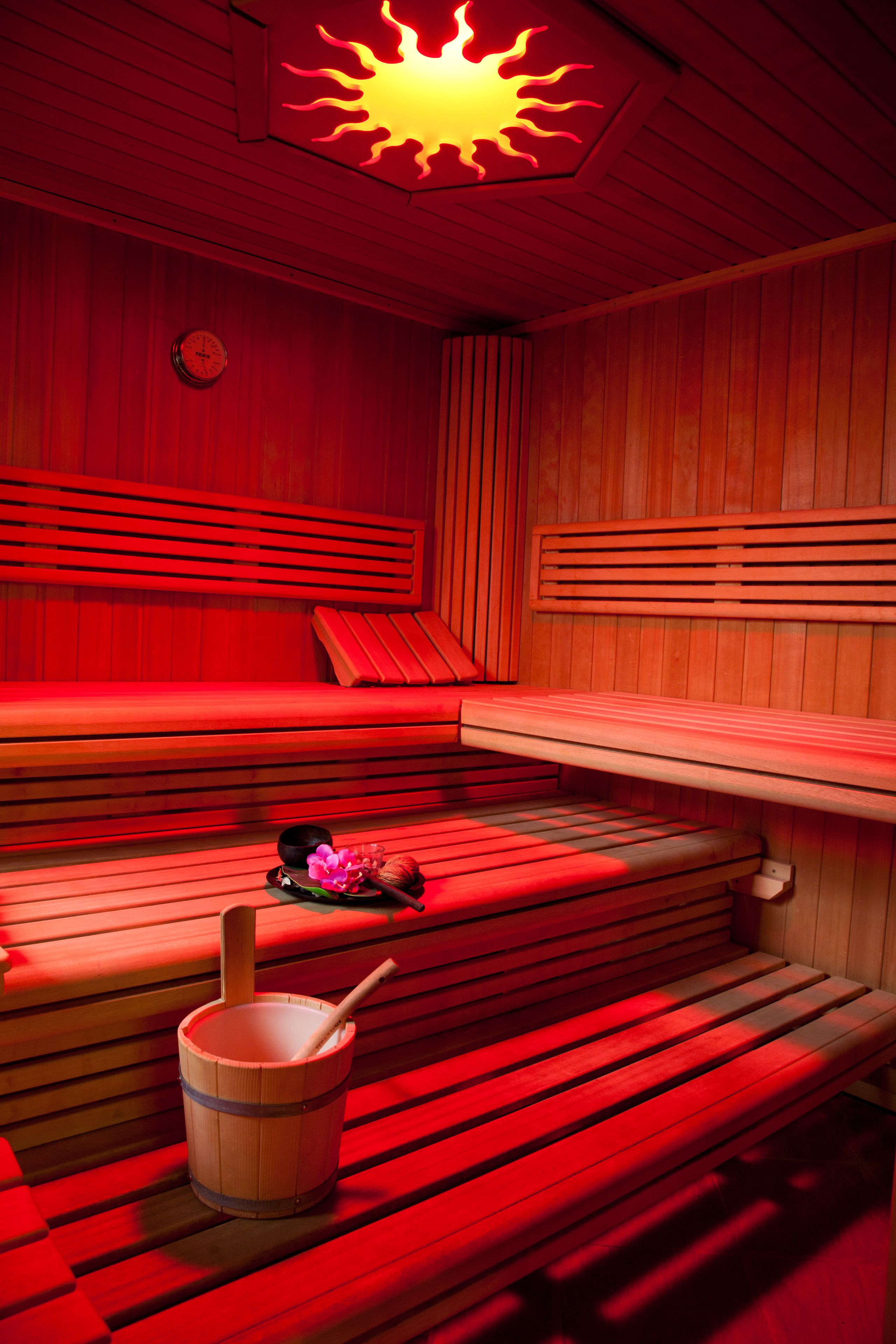 Un sauna avec des bancs en bois et un luminaire en forme de soleil.