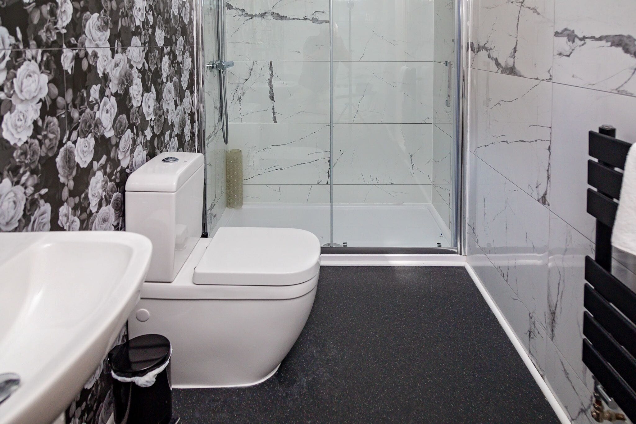 A bathroom with a toilet, sink, and shower area.