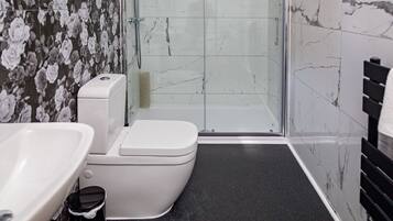 A bathroom with a toilet, sink, and shower area.