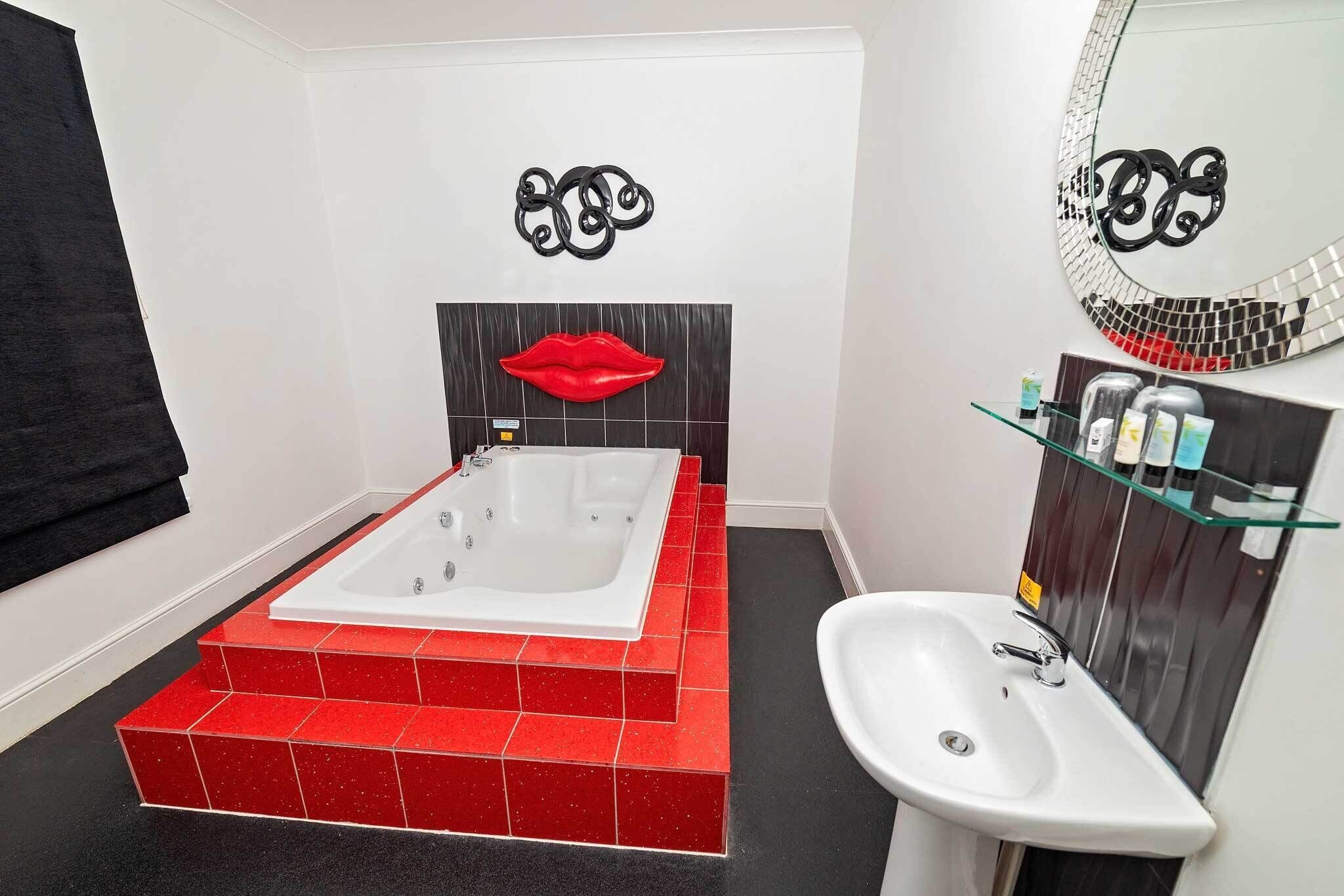 A bathroom with a large bathtub, a sink, and a mirror with a mosaic backsplash.