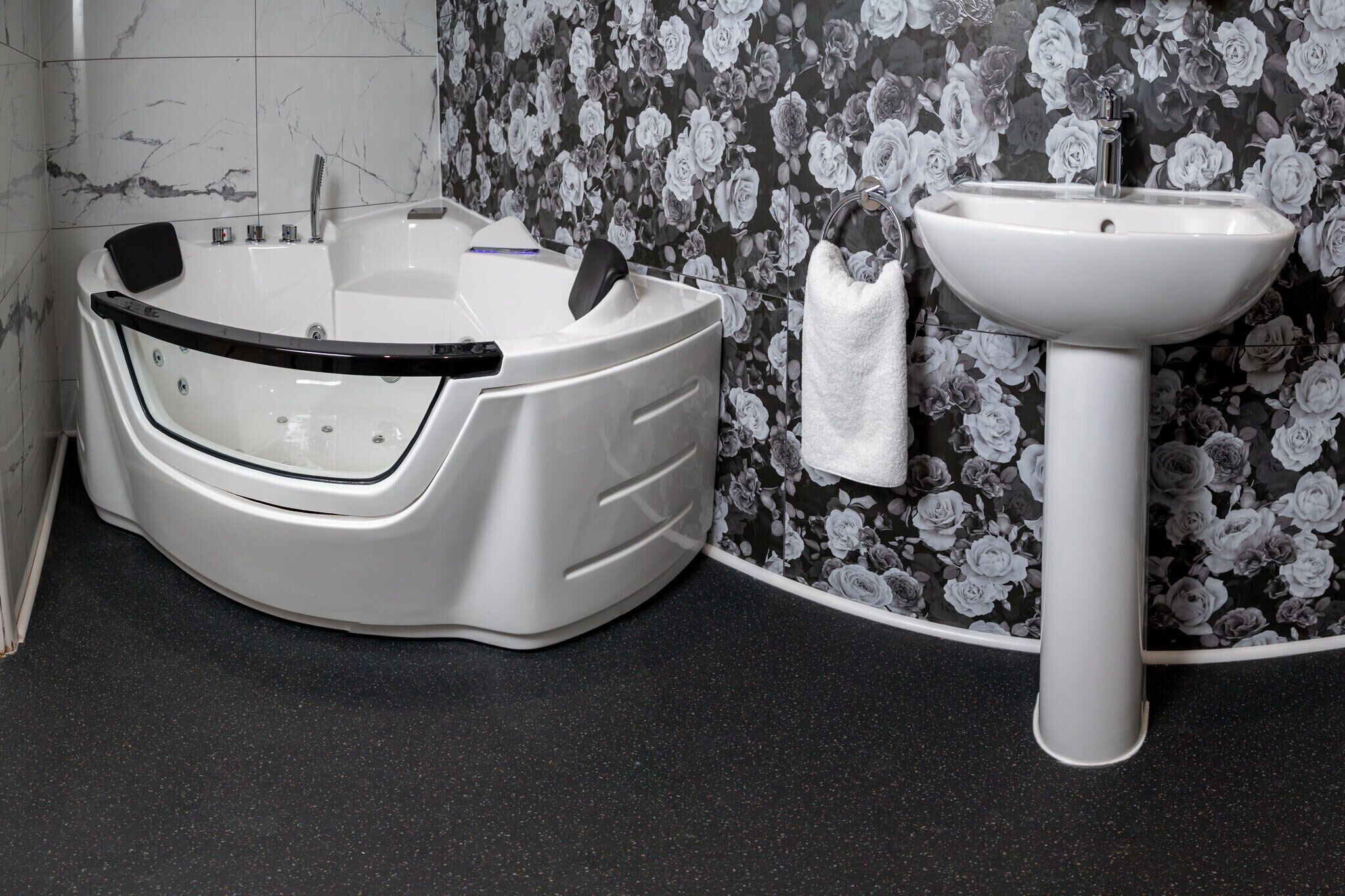 Ein Badezimmer mit einer Badewanne, einem Waschbecken und floralem Wandpapier.