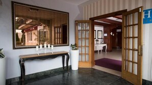 A reception area with a wooden console table, a large mirror, and a potted plant. - San Marcos (Cambados)