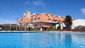 A hotel with a swimming pool, a red-roofed building, and a palm tree. - San Marcos (Cambados)