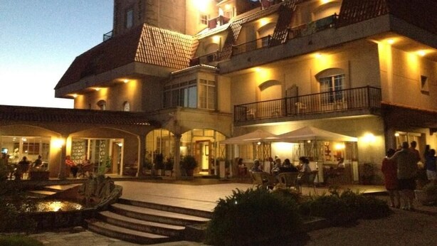 A multi-story building with a courtyard, outdoor seating, and a water feature. - San Marcos (Cambados)