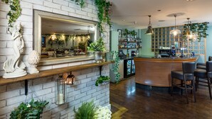A bar area with a brick wall, hanging plants, and a counter with stools. - Hotel Penzance Harbour View (Penzance)