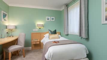 A bedroom with a bed, a desk, a chair, a nightstand, and a window with curtains.