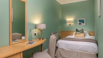 Una habitación de hotel con cama, mesita de noche, lámpara y espejo.