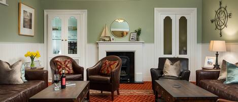 A traditional living room with leather sofas, a fireplace, and a patterned carpet.