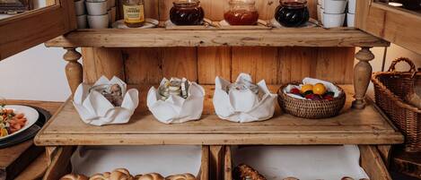 Een houten buffet met potten jam, een mand vol fruit en brood.