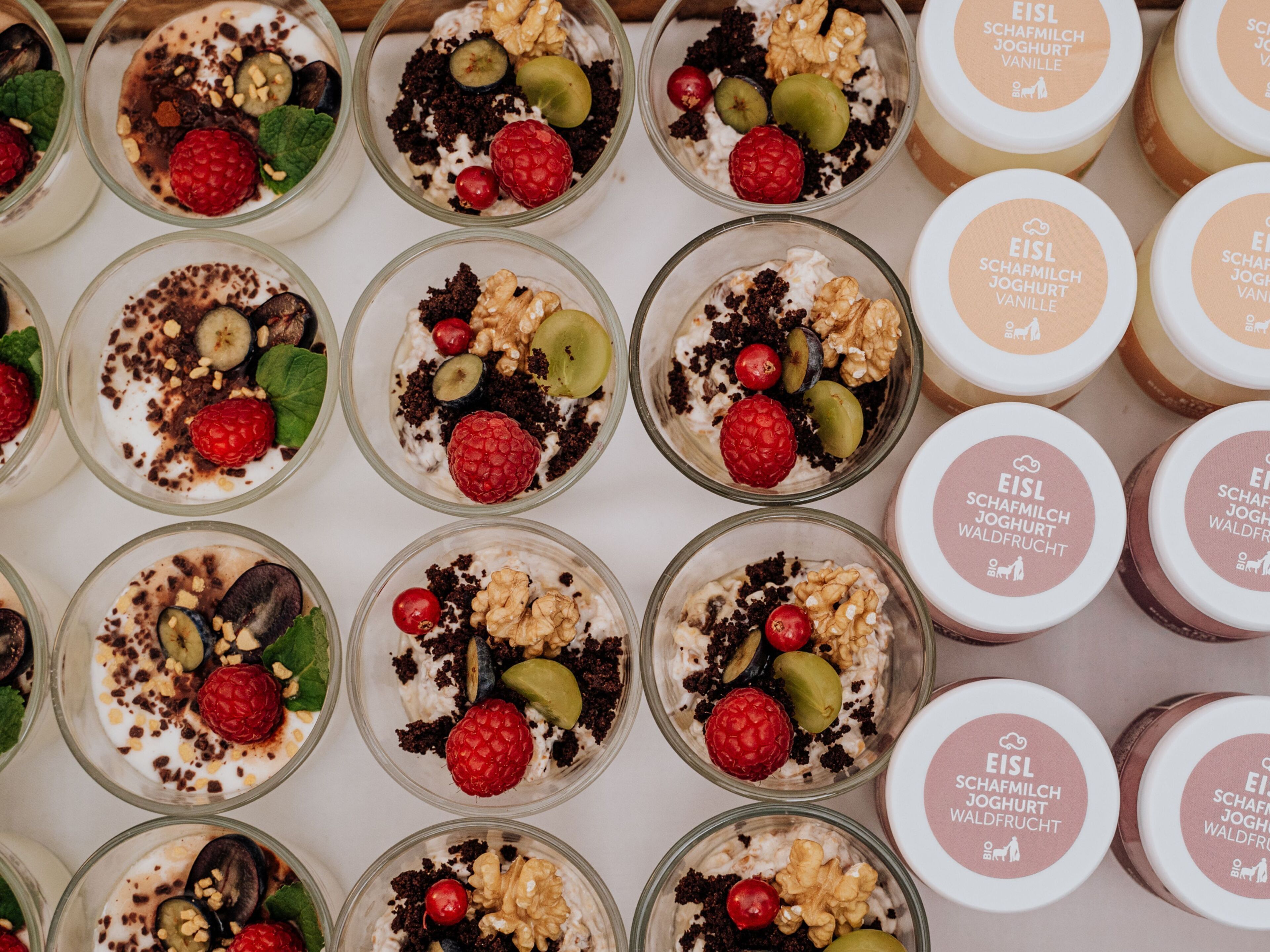 Varios vasos con parfait de yogur, con diferentes ingredientes, dispuestos sobre una mesa.