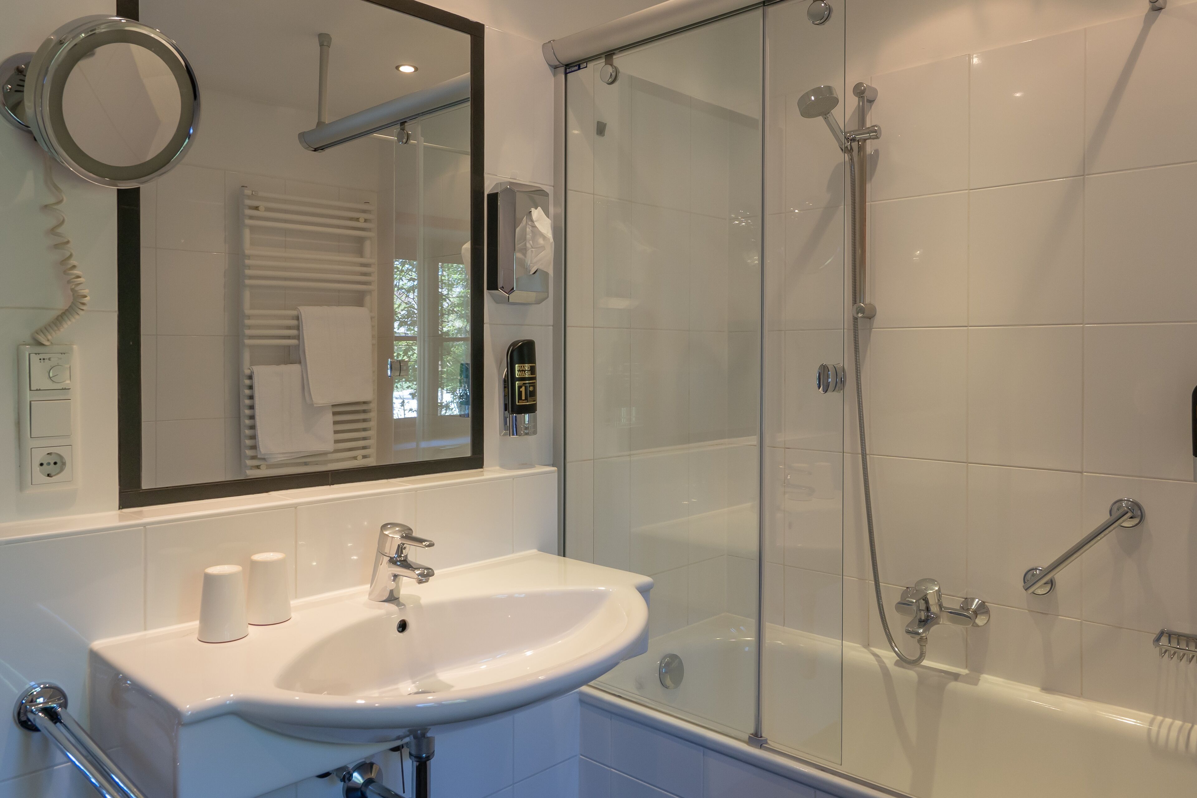 Een moderne badkamer met een douchecabine van glas, een wit wastafelmeubel en een spiegel erboven.