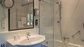 Een moderne badkamer met een douchecabine van glas, een wit wastafelmeubel en een spiegel erboven.