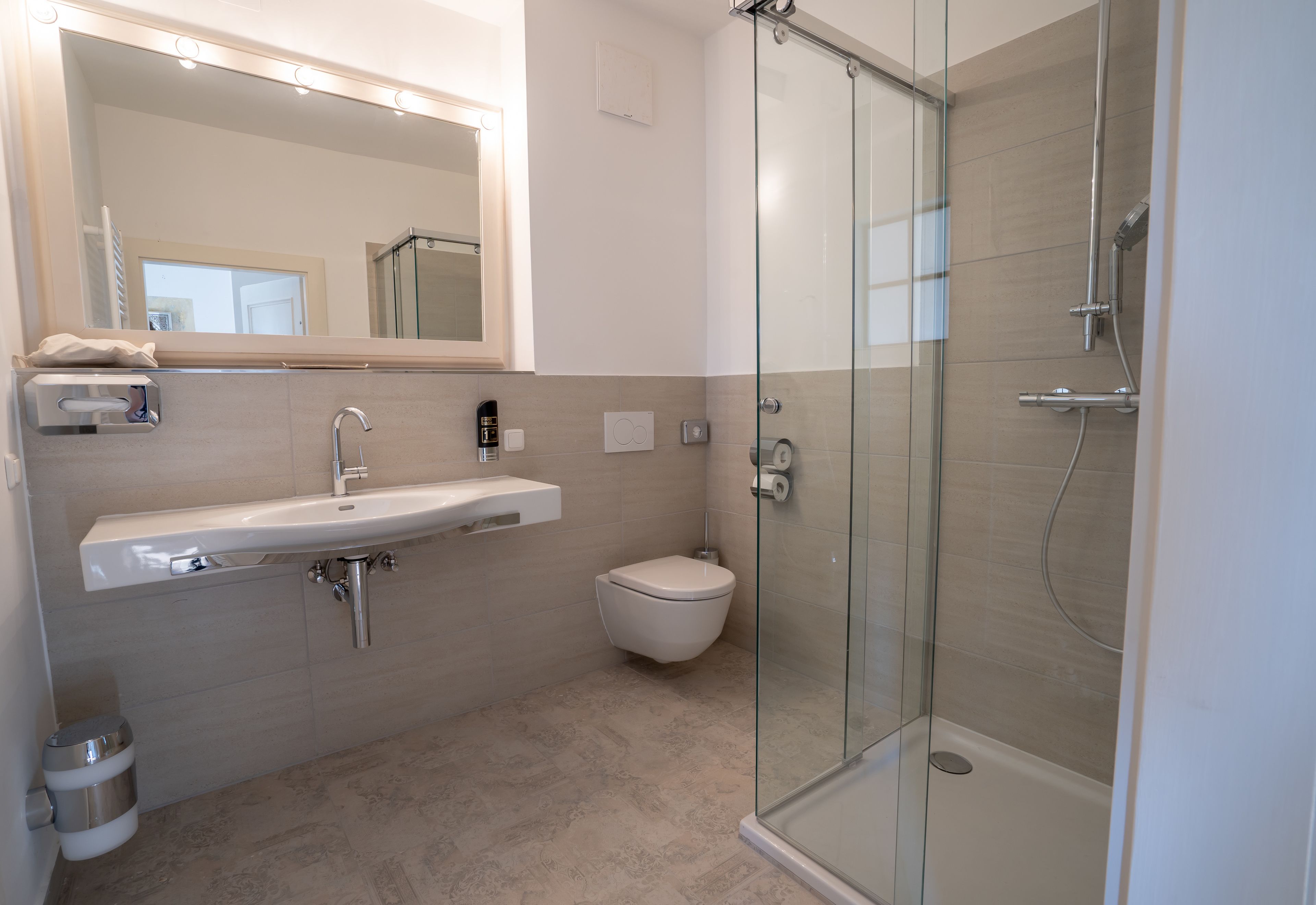 A modern bathroom with a glass-enclosed shower, a white sink, and a toilet.