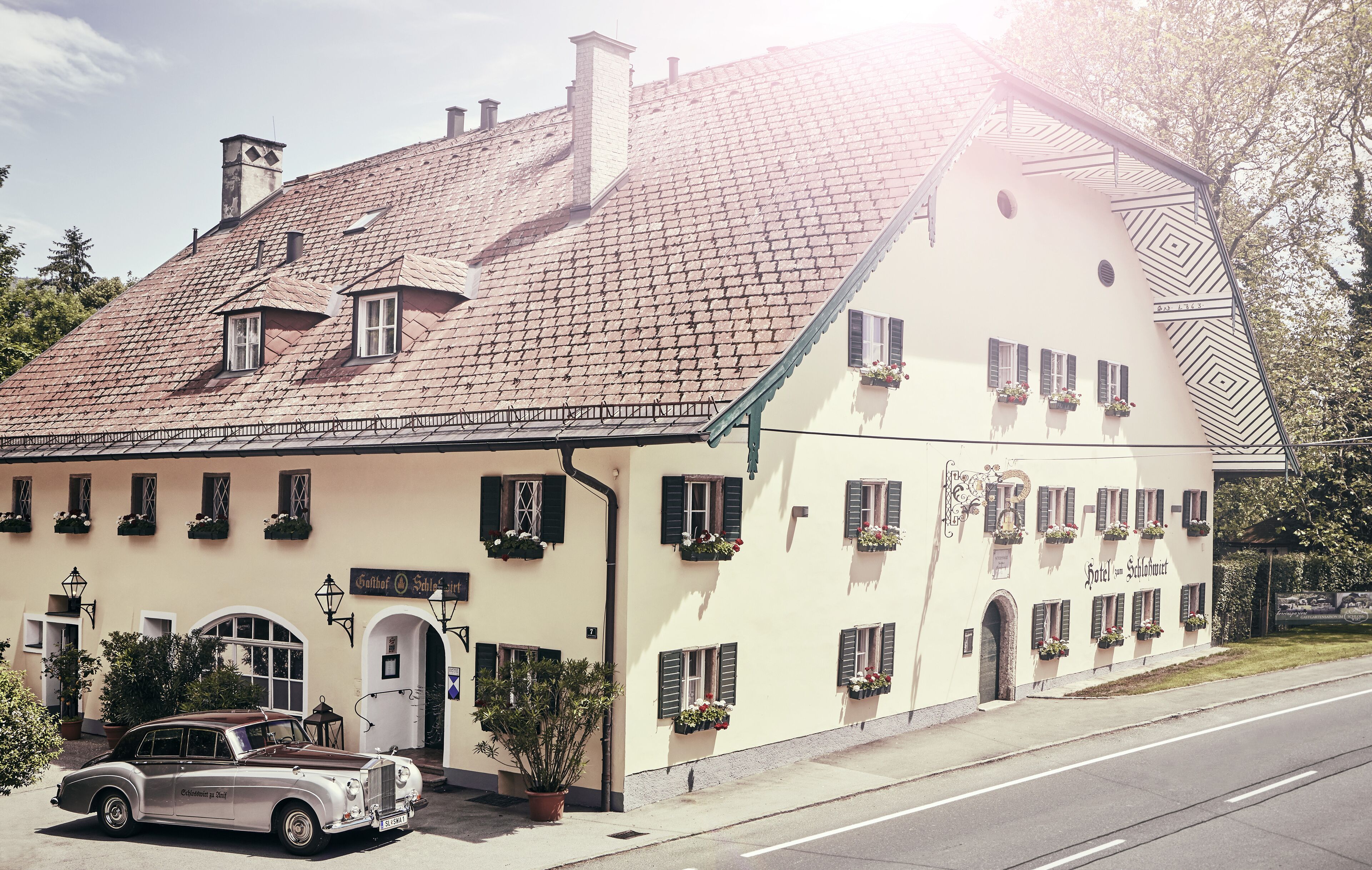 A traditional building with a sloped roof, multiple windows with shutters, and a sign indicating it is a hotel.
