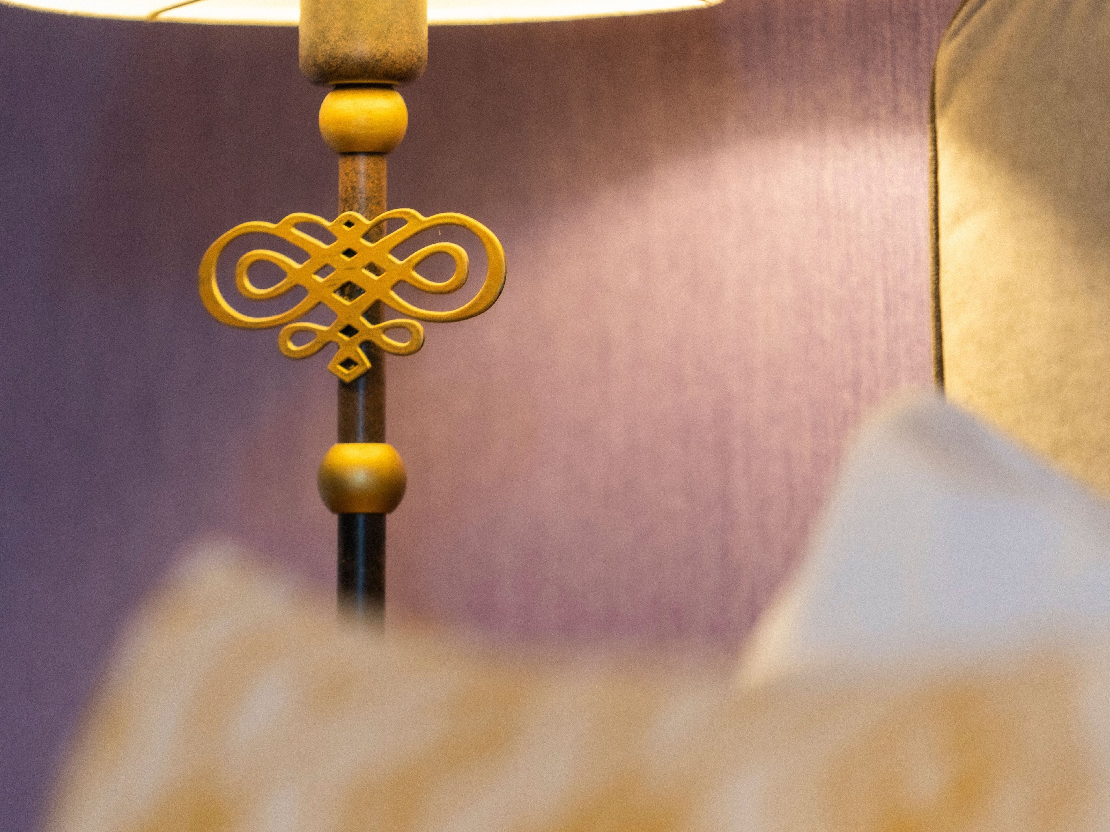 A close-up of a lamp with a decorative key-shaped metal piece and wooden beads.