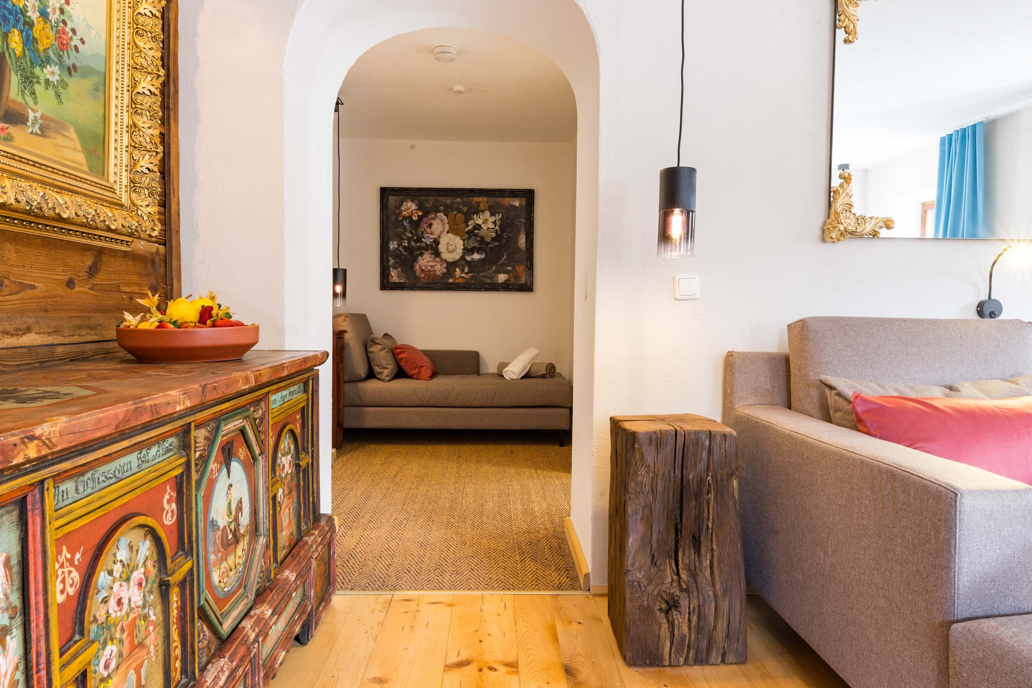 A living room with a sofa, a wooden coffee table with a bowl, a painting, and a mirror.