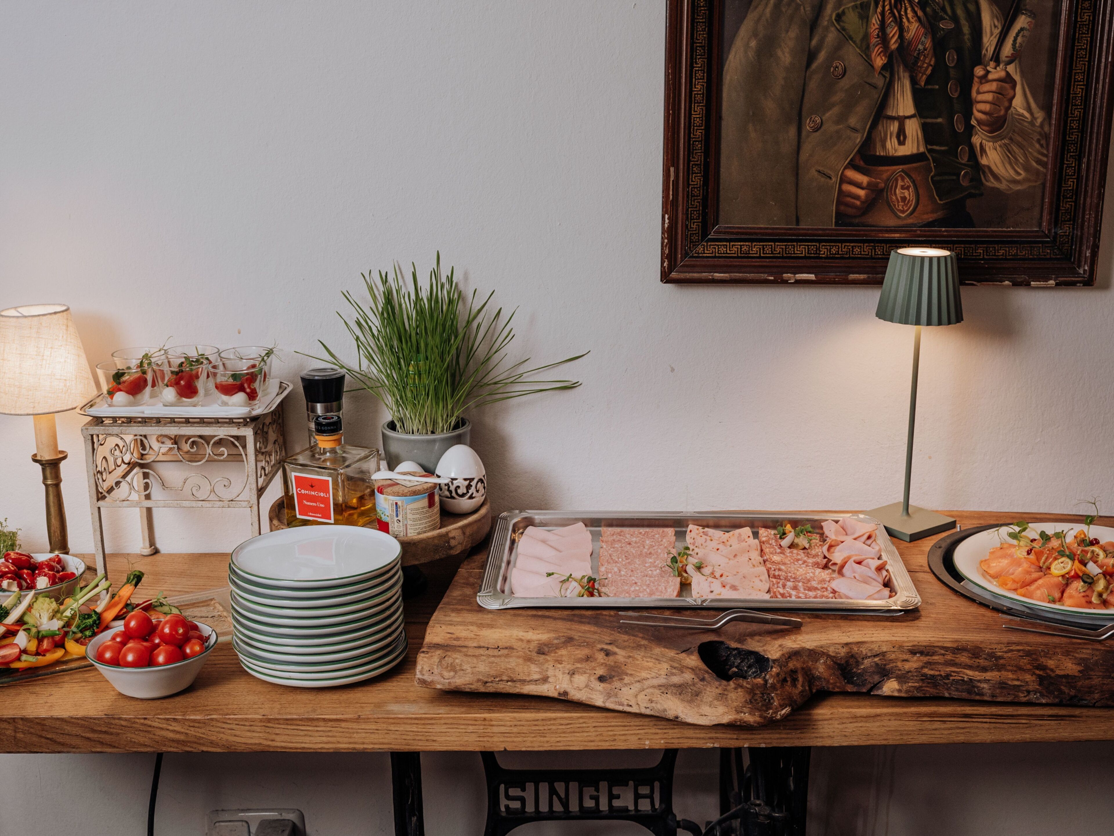 A dining table with various food items, a lamp, and a framed painting.