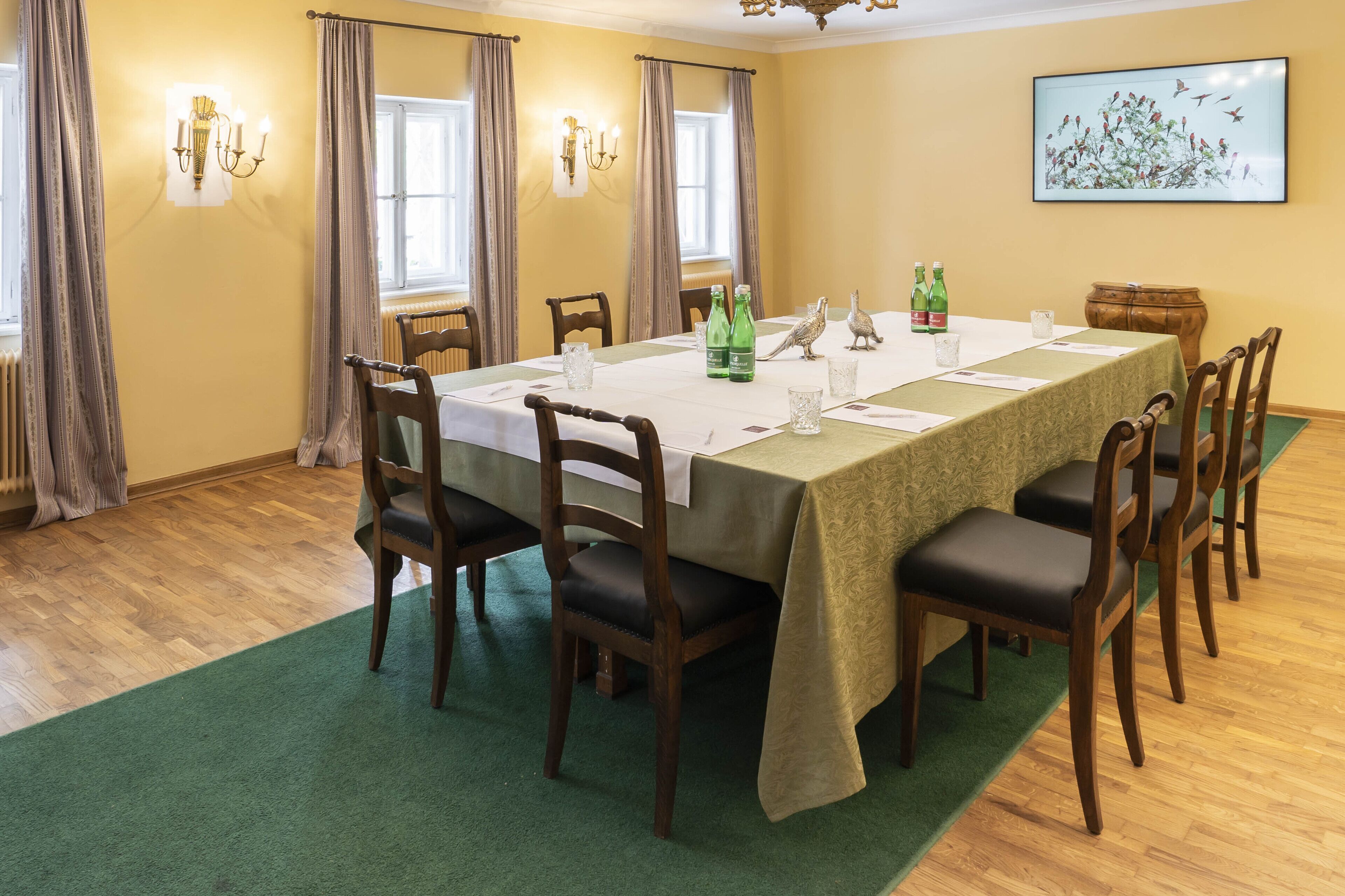 A dining room with a long table, chairs, and a chandelier.