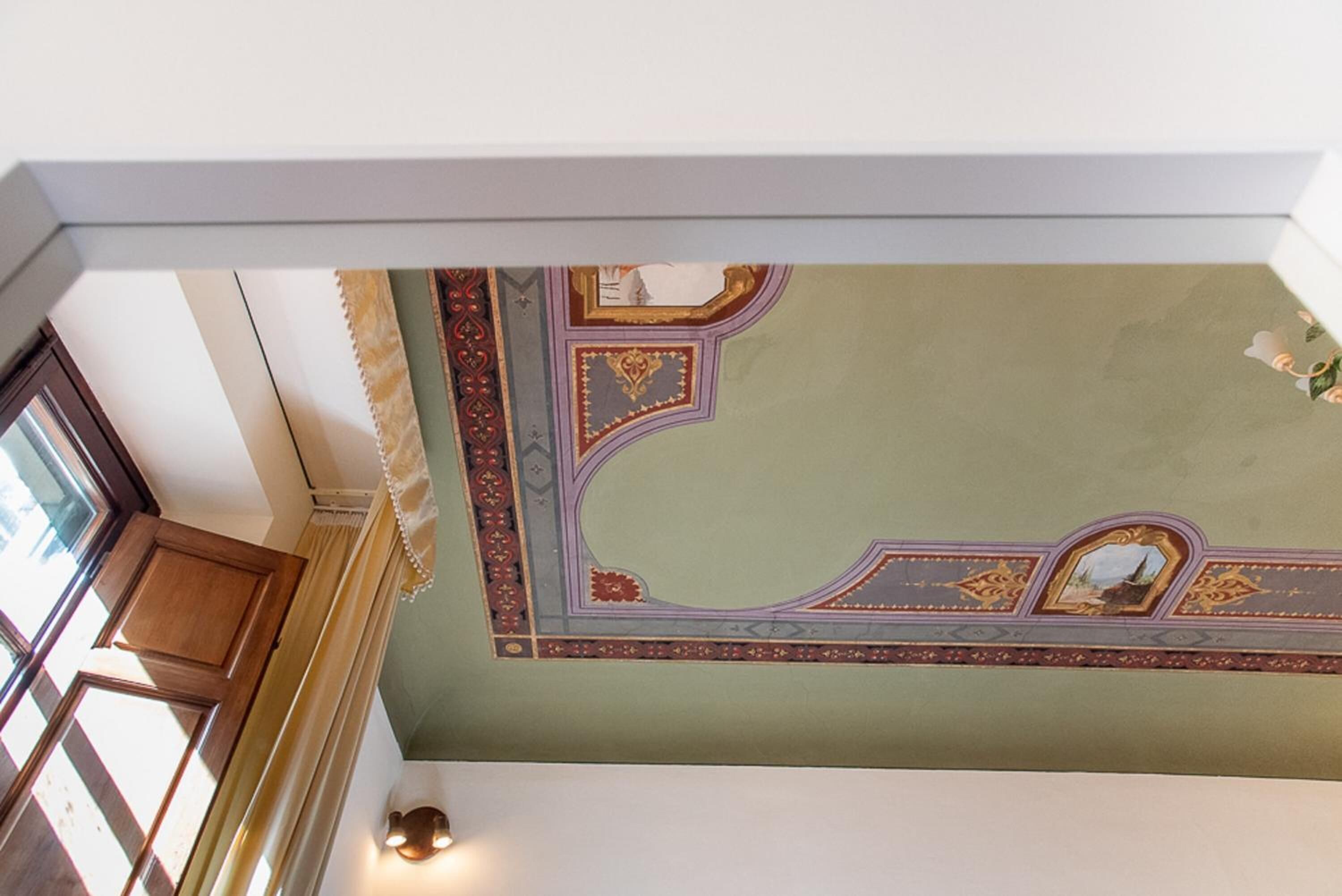 A room with a green ceiling featuring ornate gold and red decorative elements.