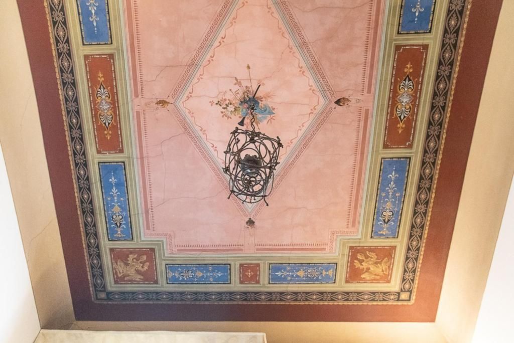 A ceiling with a geometric pattern and a central chandelier.