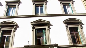 Ein mehrstöckiges Gebäude mit einem zentralen Eingang, der eine große Holztür und einen verzierten Bogen aufweist.