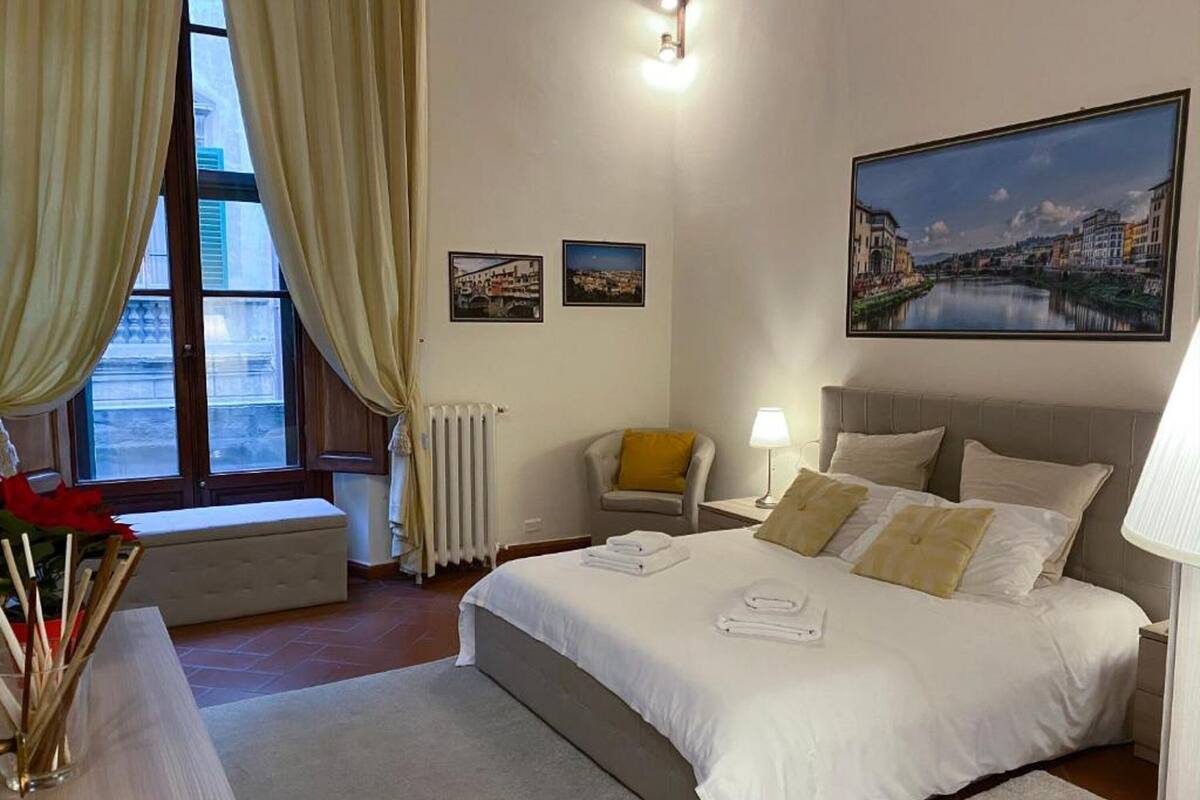 Une chambre d’hôtel avec un grand lit, une chaise, un bureau et une fenêtre avec des rideaux.