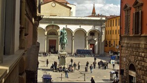 Ein öffentlicher Platz mit einer Statue, historischen Gebäuden und blauem Himmel.