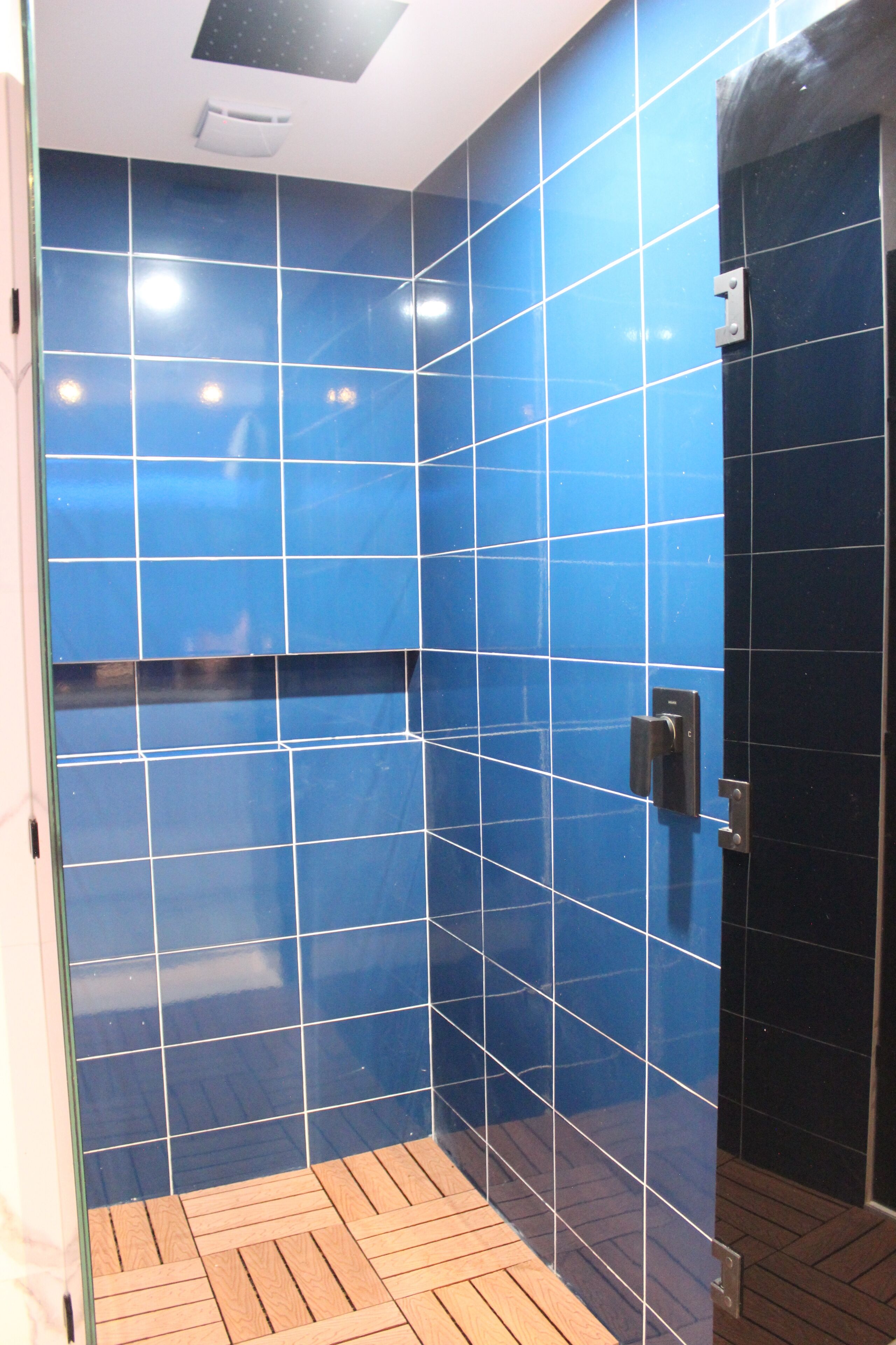 A bathroom with blue tiled walls and a wooden floor.