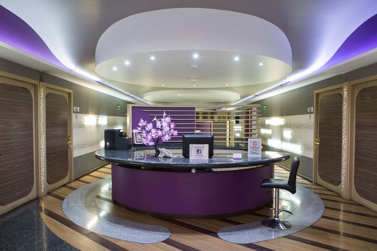 A reception desk with a purple counter, a phone, and a flower arrangement.