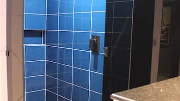 Un baño con paredes de azulejos azules, suelo de madera y zona de ducha.