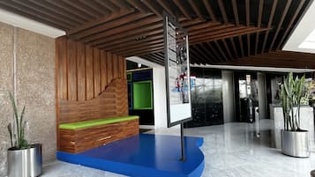 Una hall moderna con un soffitto in listelli di legno, una reception blu e un pavimento in marmo.