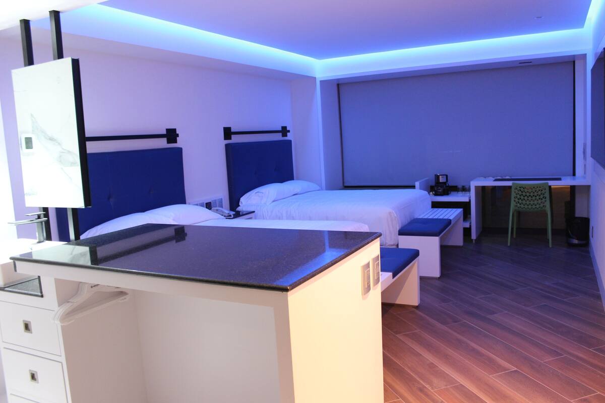 A modern hotel room with a bed, bedside table, desk, and chair.