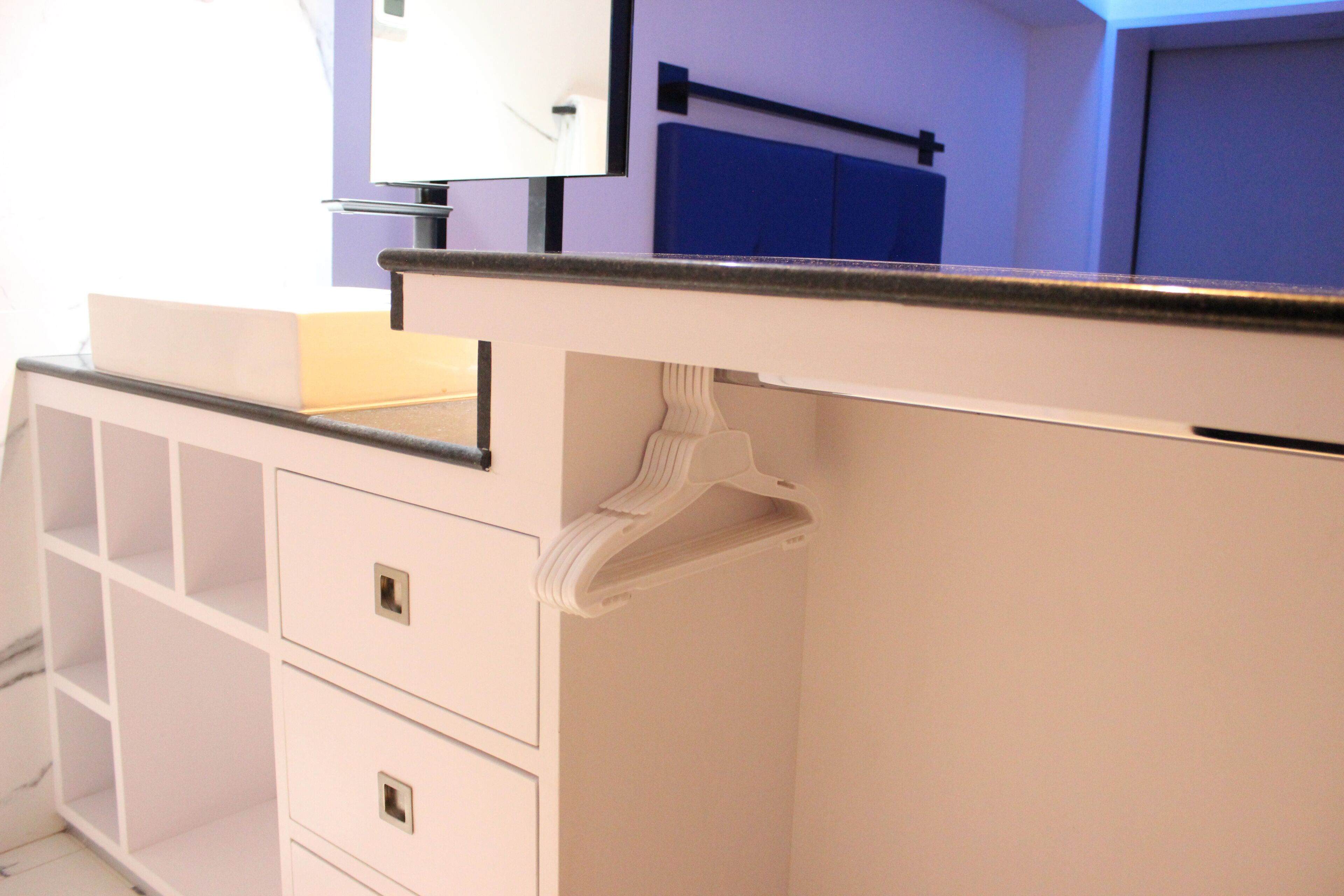 A white bathroom vanity with a mirror, a sink, and a towel rack.