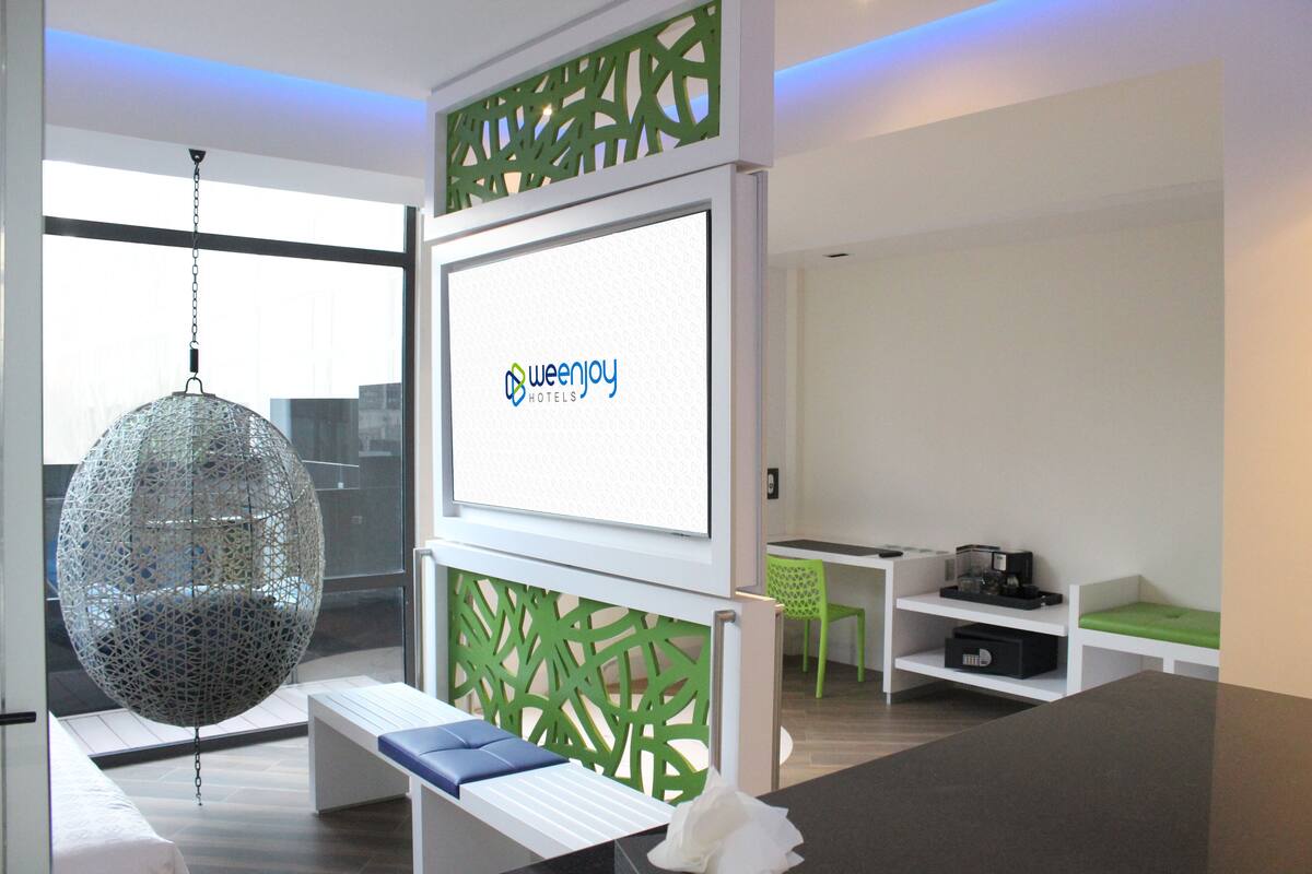 A modern hotel reception area with a large digital display, a hanging spherical light fixture, and a green decorative partition.
