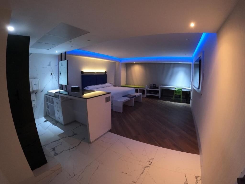 A modern hotel room with a bed, a desk, and a small seating area.