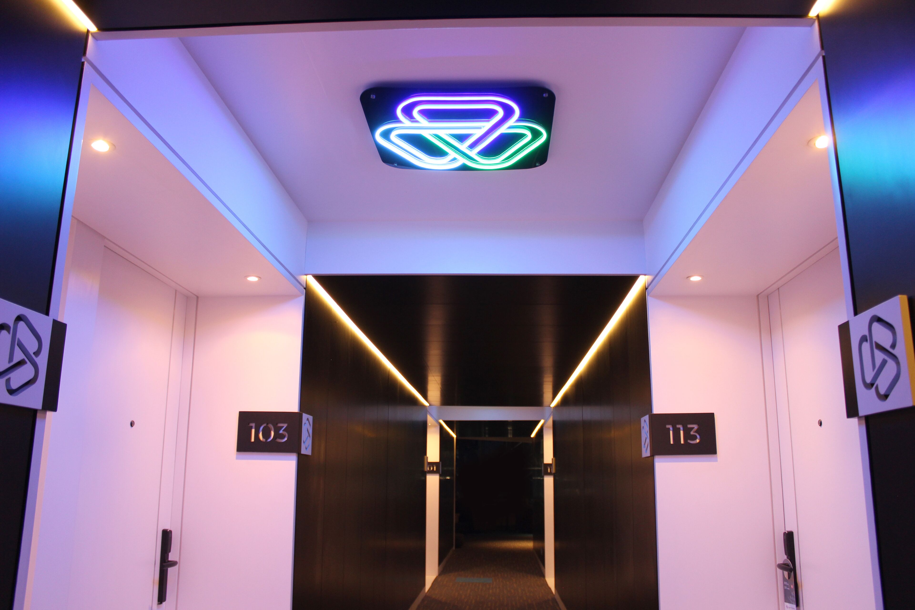 Entrada d'un ascensor amb senyalització il·luminada i els números de pis 103 i 113.