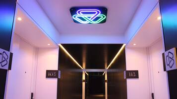 Entrada de ascensor con señalización iluminada y los pisos 103 y 113.