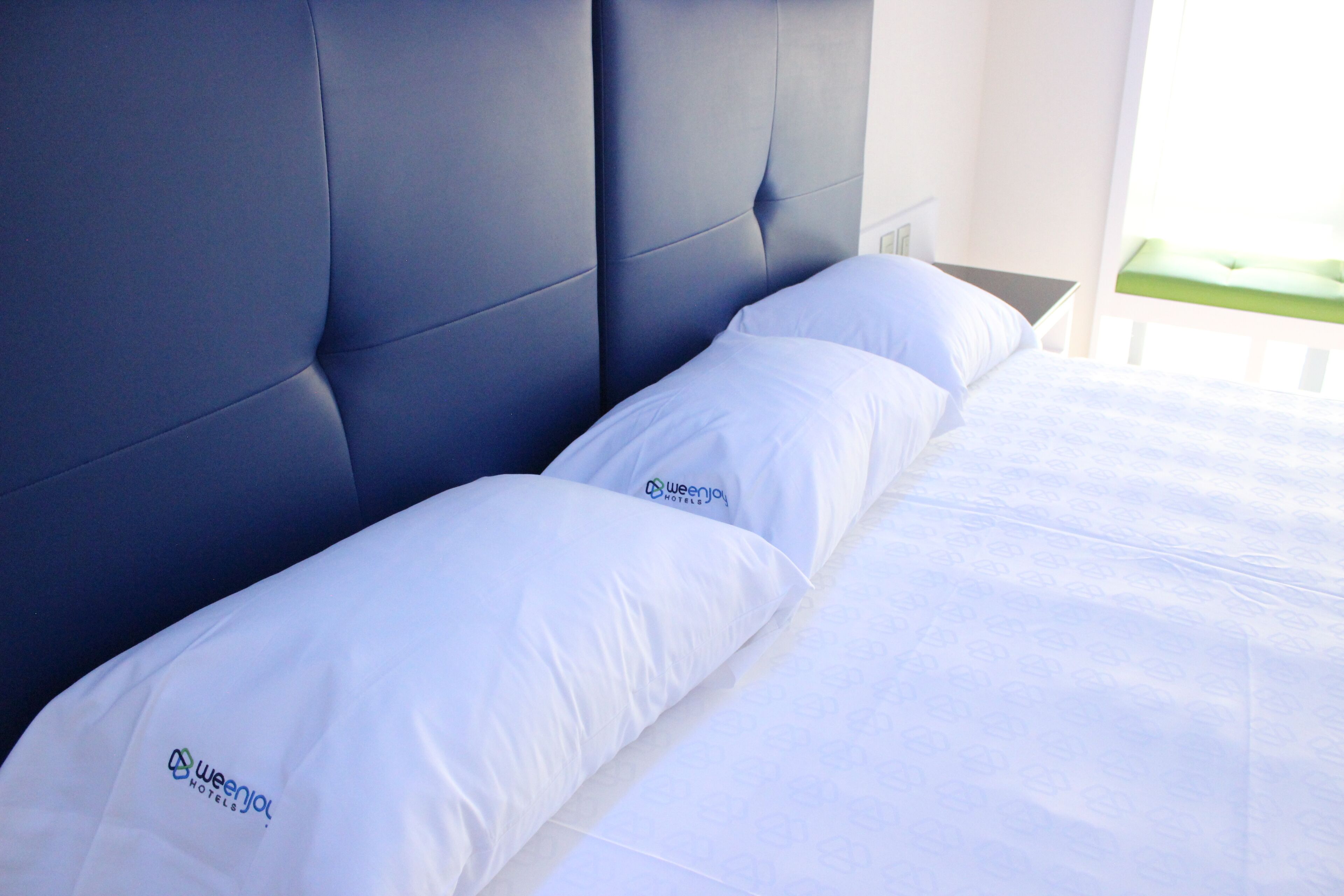 A hotel room with a large bed, two white pillows, and a headboard.