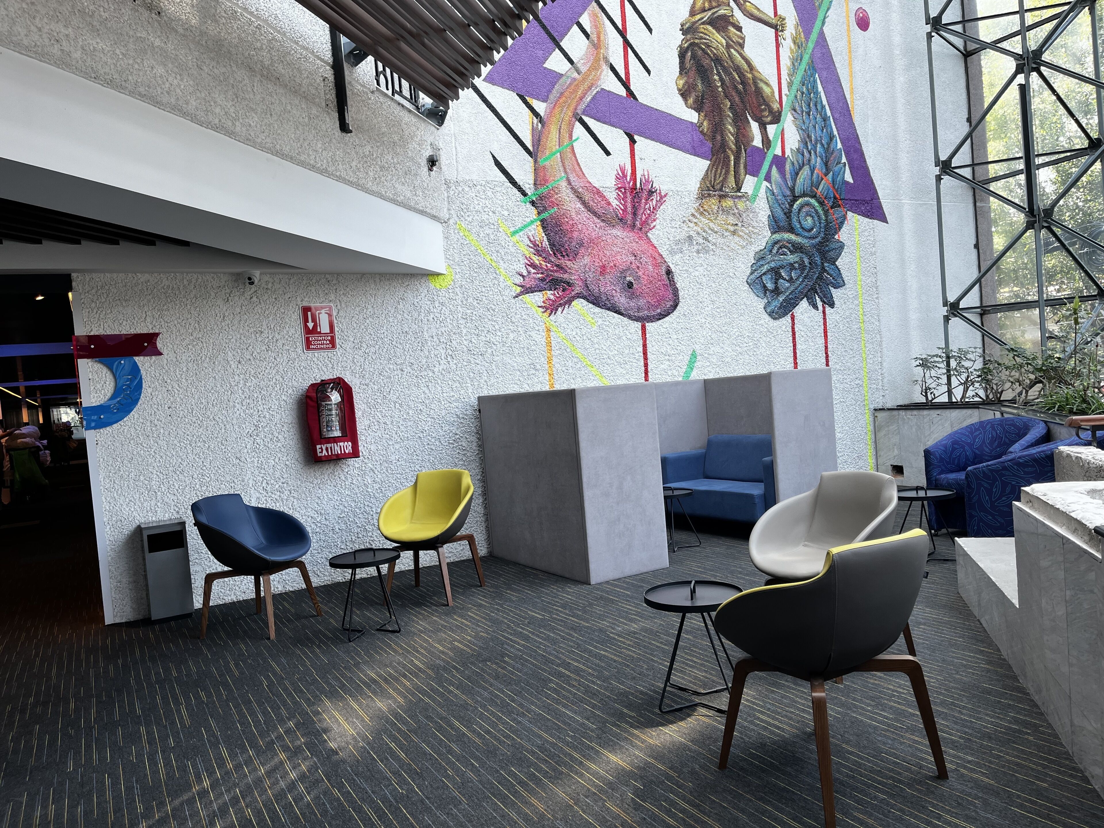 A modern interior with a mural, seating area, and a fire extinguisher.