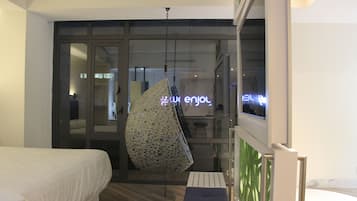 Una habitación de hotel con una cama, una silla colgante y vista a la calle.