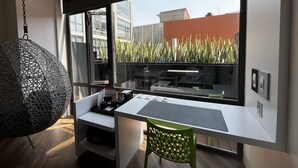 A modern room with a large window, a hanging chair, a desk, and a green chair.