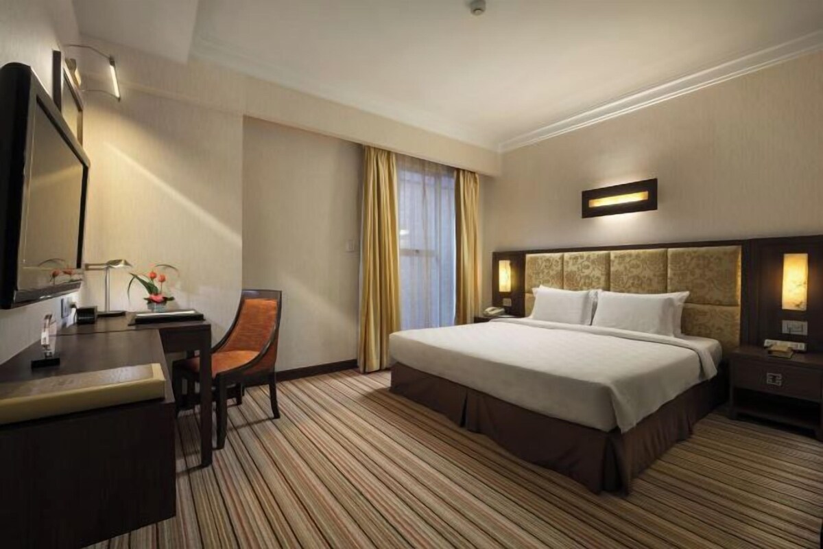 A hotel room with a bed, desk, chair, and a television.