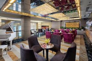 A spacious lobby with a grand piano, plush seating, and a chandelier.