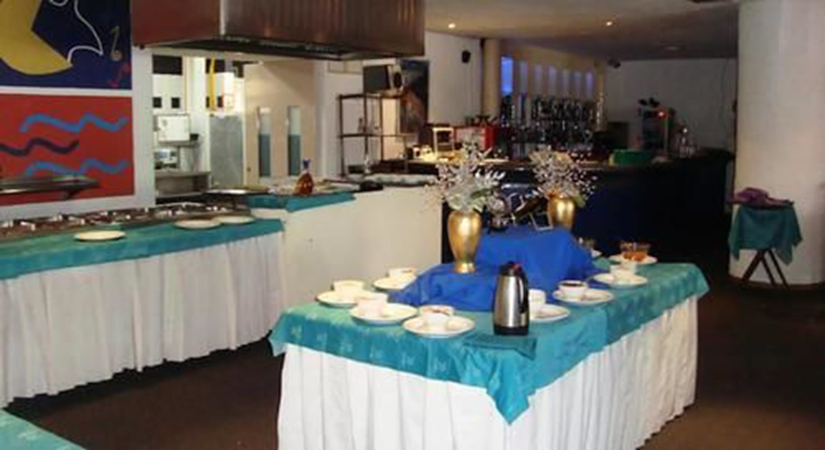 Montaje de bufé con varias mesas cubiertas de manteles azules, caminos de mesa blancos y diferentes platos.